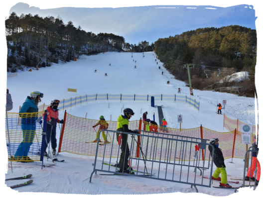 Kinder fahren an einem kleinen Skilift einen verschneiten Hang hinunter